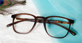 Exquisite blue cut brown eyeglasses placed on blue and white fabric